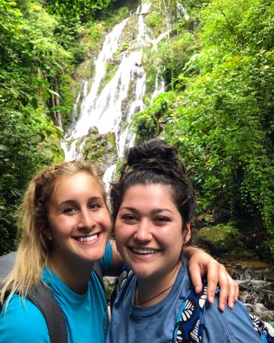Chelsea White standing in front of a waterfall in the Panama jungle with Morgan Cheramie.