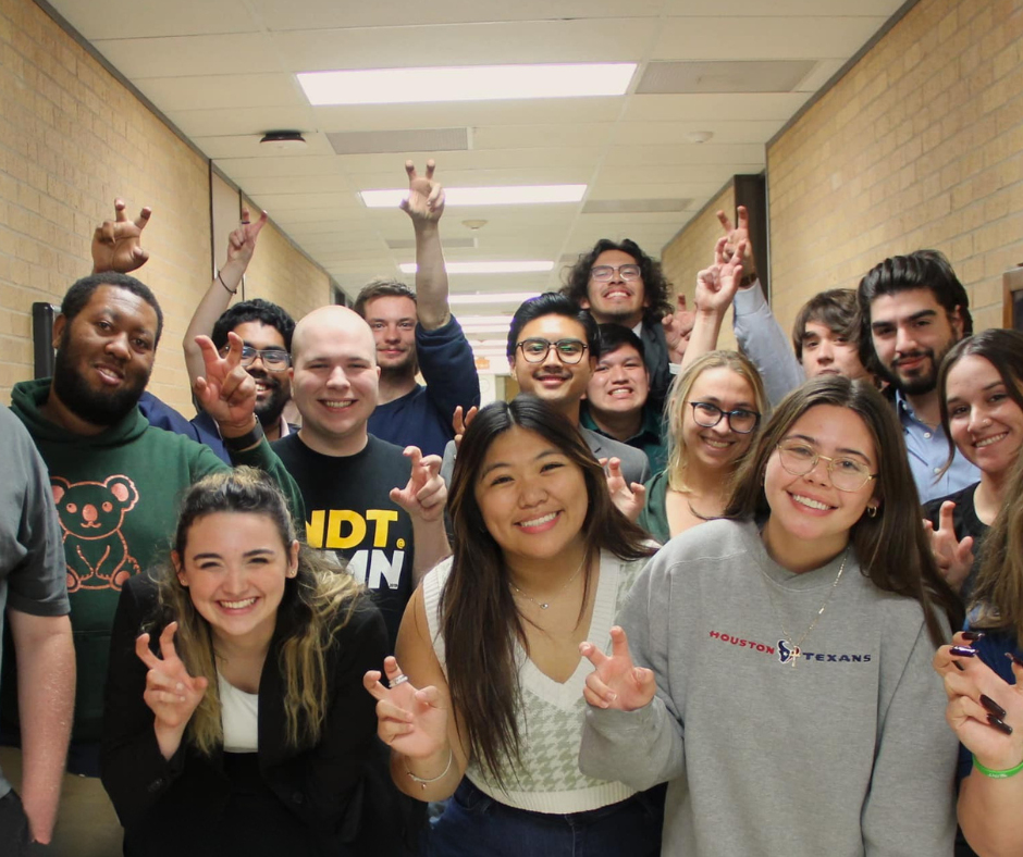 UNT Debate team members smiling and posing with UNT claw