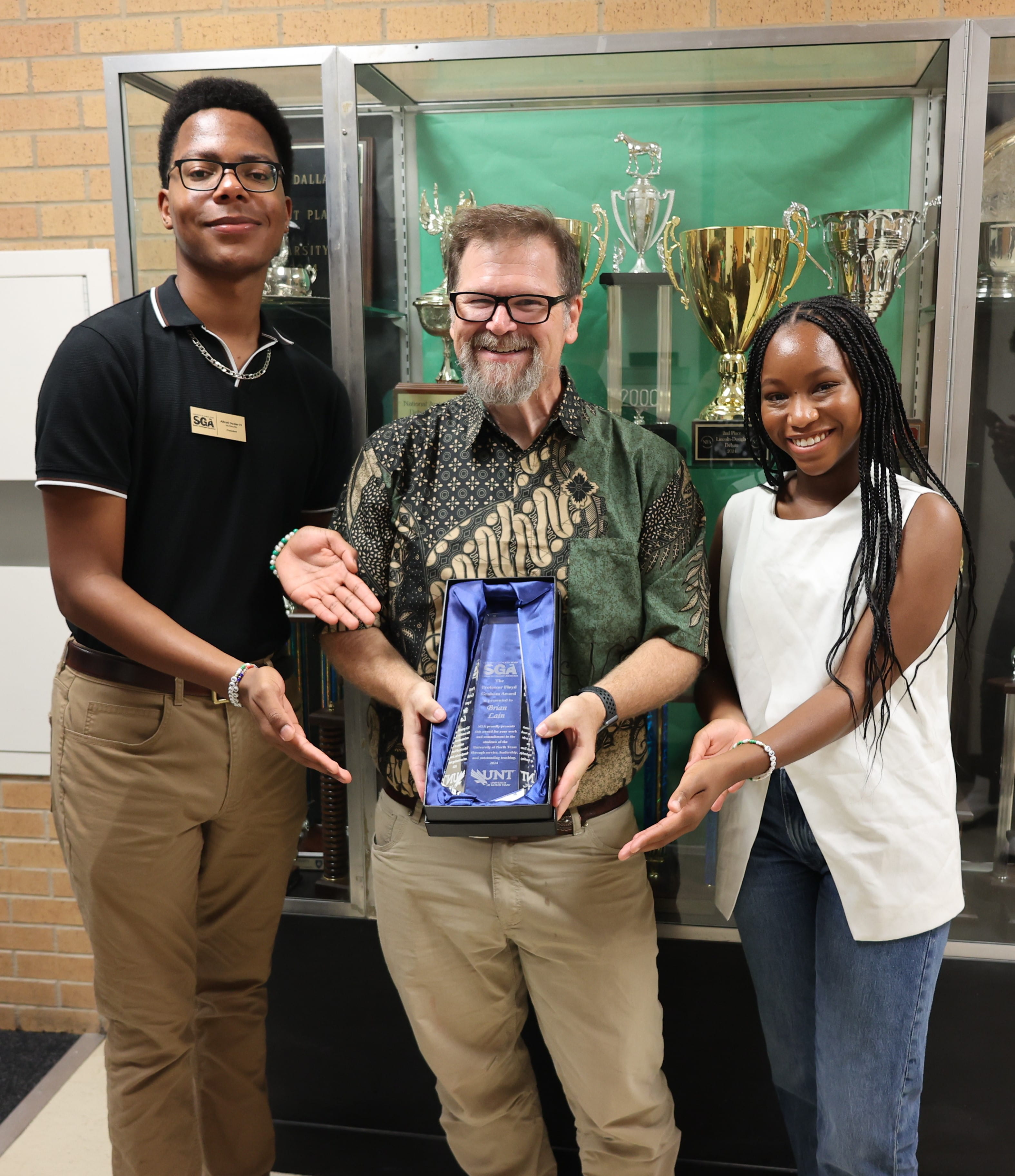 Dr. Brian Lain holding 'Fessor Graham Award with SGA officers on either side of him