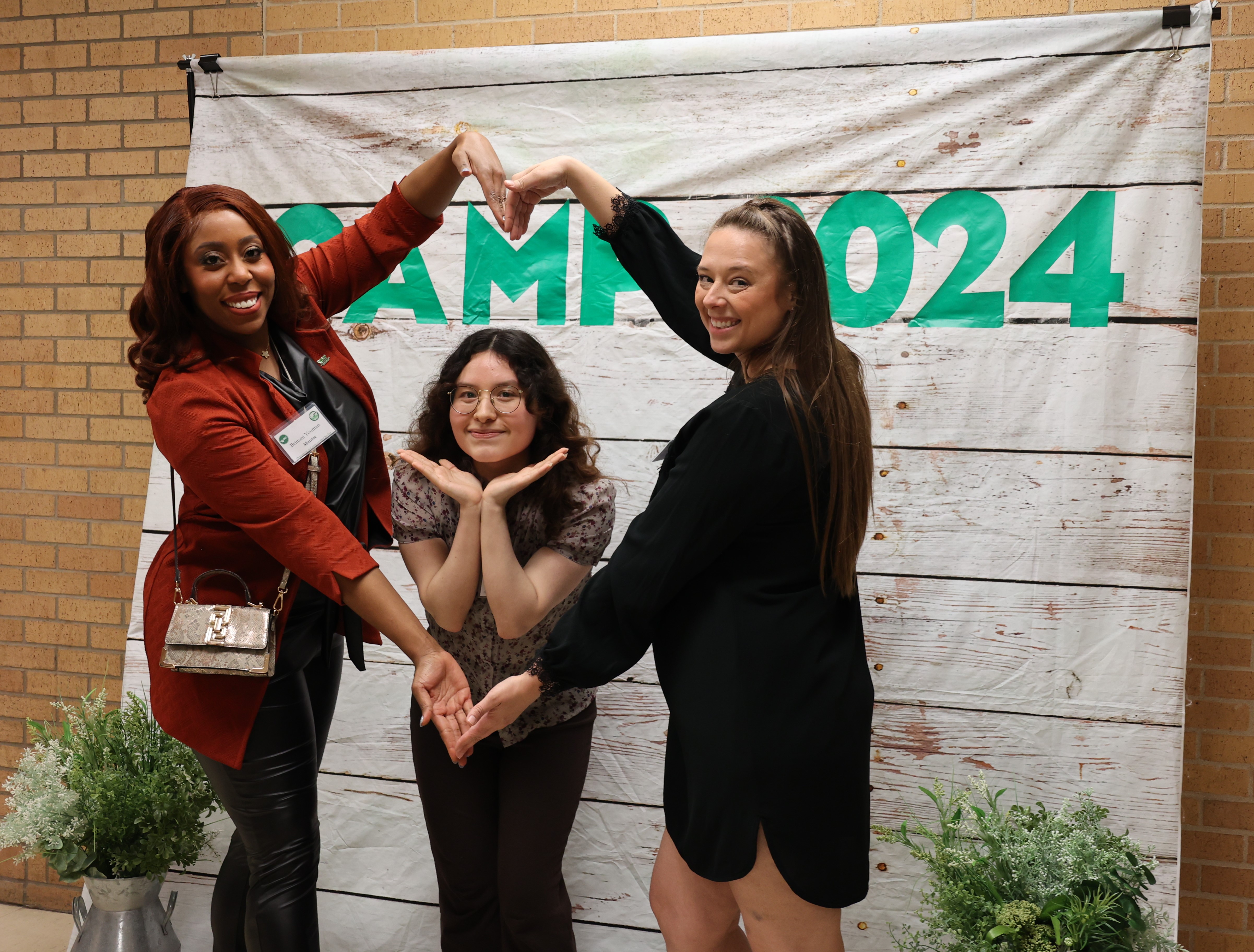 3 participants in front of CAMP 2024 backdrop