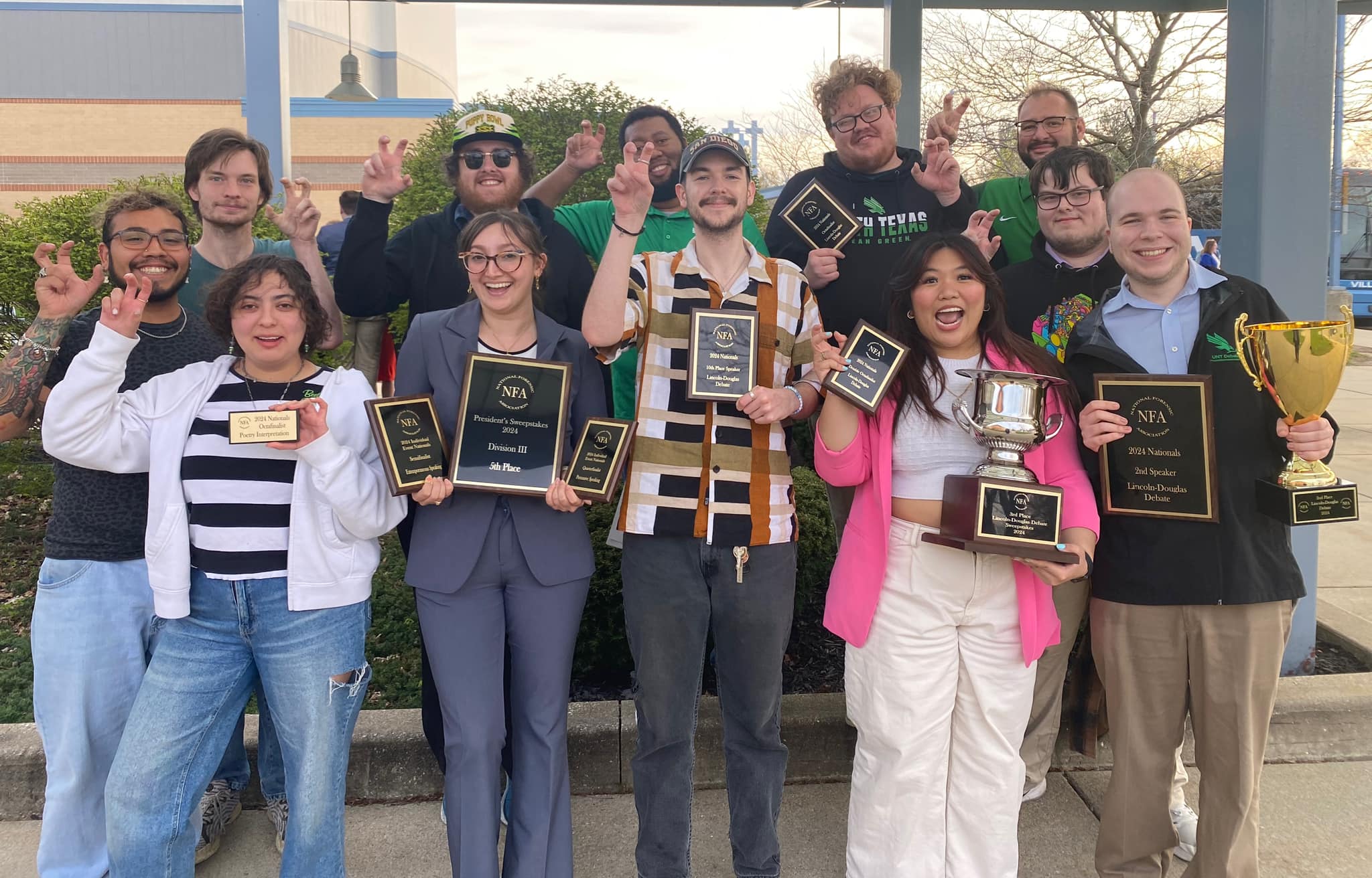 UNT Debate team holding their plaques, trophies, and awards from the 2023-2024 season